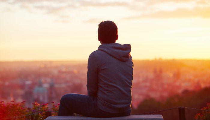 Young man is looking at the sunrise.